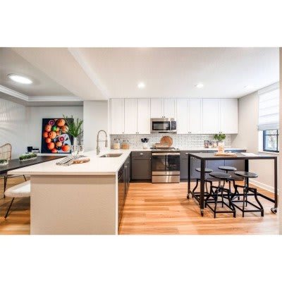A modern kitchen with white cabinets, an island, and hardwood floors.