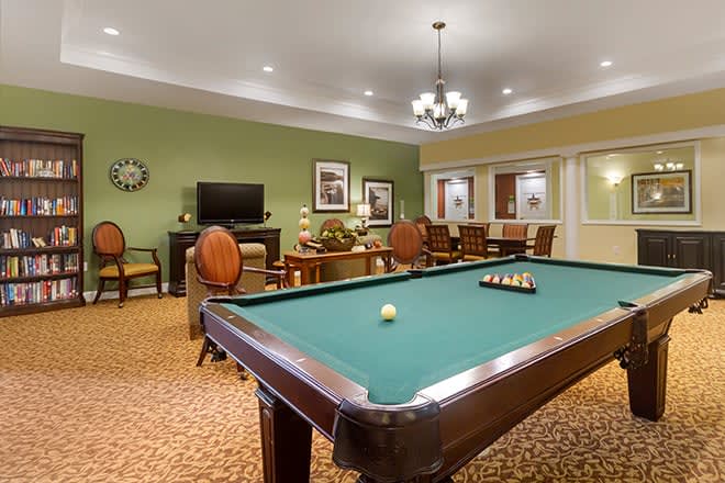 A cozy recreation room featuring a billiards table and comfortable seating.