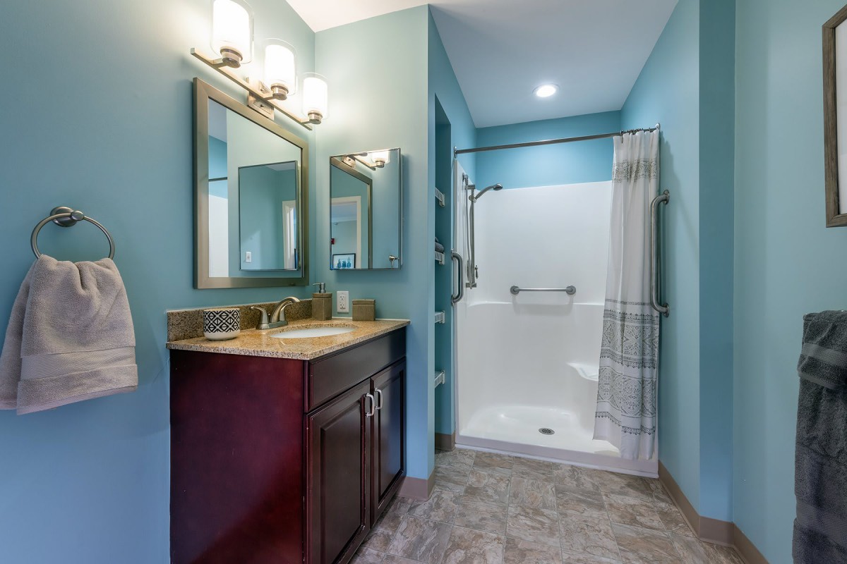 A modern bathroom with a shower, vanity, and mirror.
