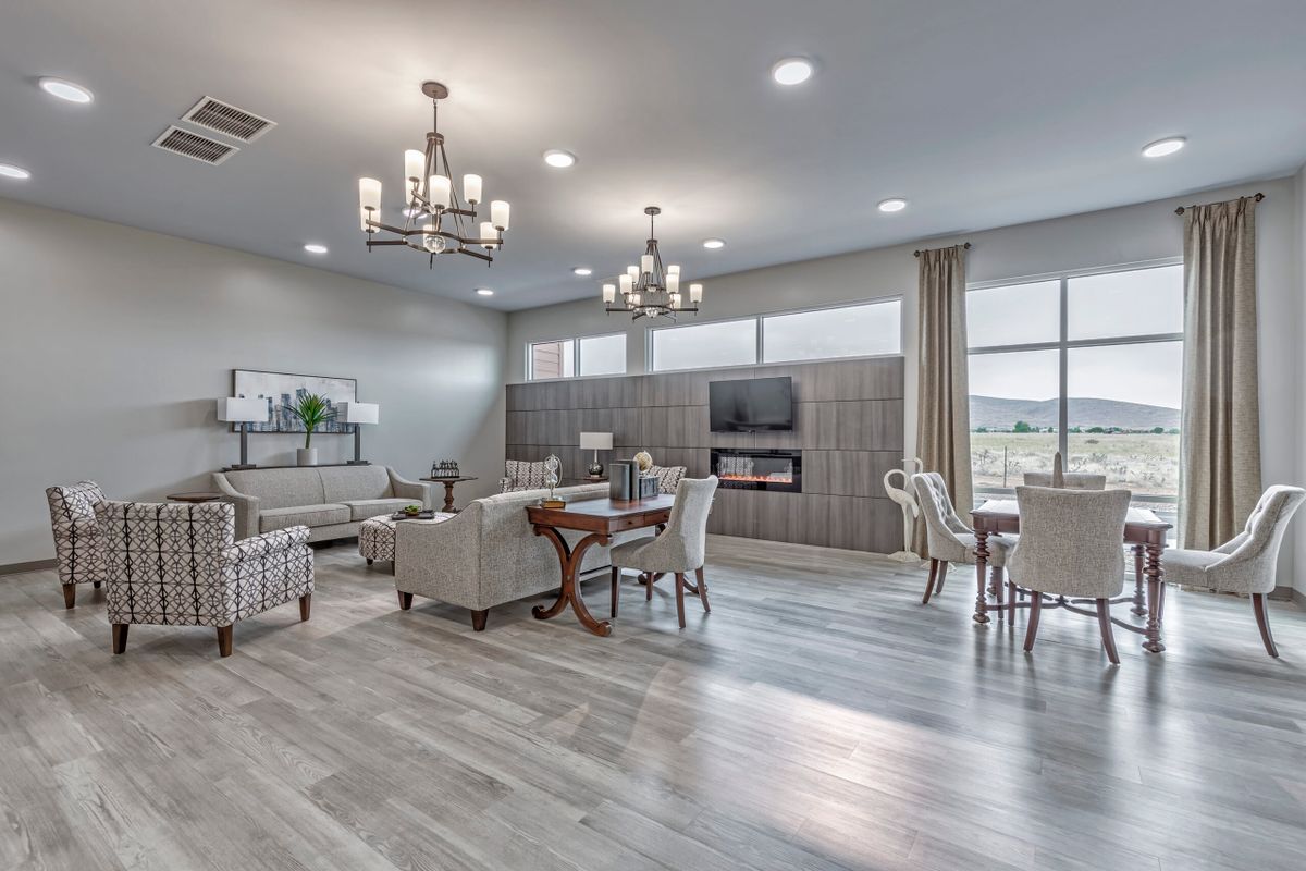 A modern and spacious living room with elegant chandeliers, comfortable seating, and large windows.