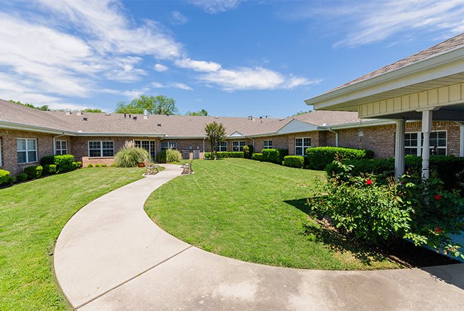 A well-maintained building with a curved pathway and landscaped lawn under a blue sky.