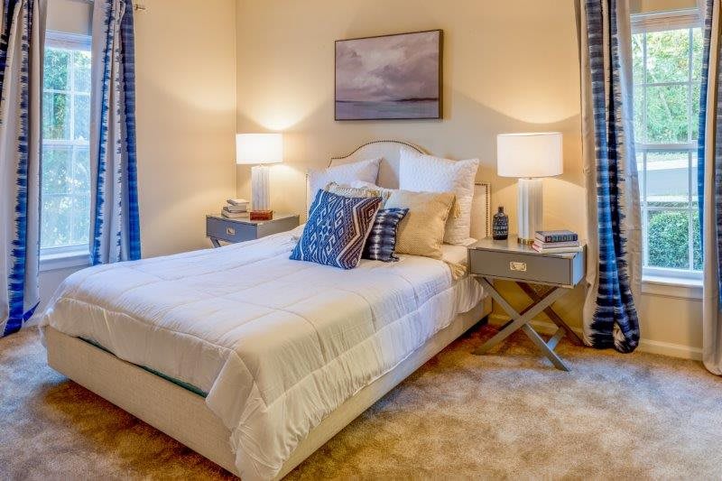 A cozy bedroom with a neatly made bed, accent pillows, and bedside lamps on nightstands.