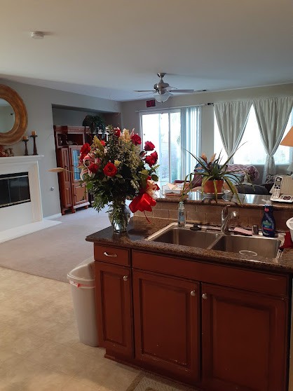 A cozy open-concept kitchen and living room with a floral centerpiece and a fireplace.