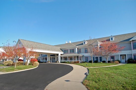 A large building with a driveway and well-maintained landscaping under a clear blue sky.