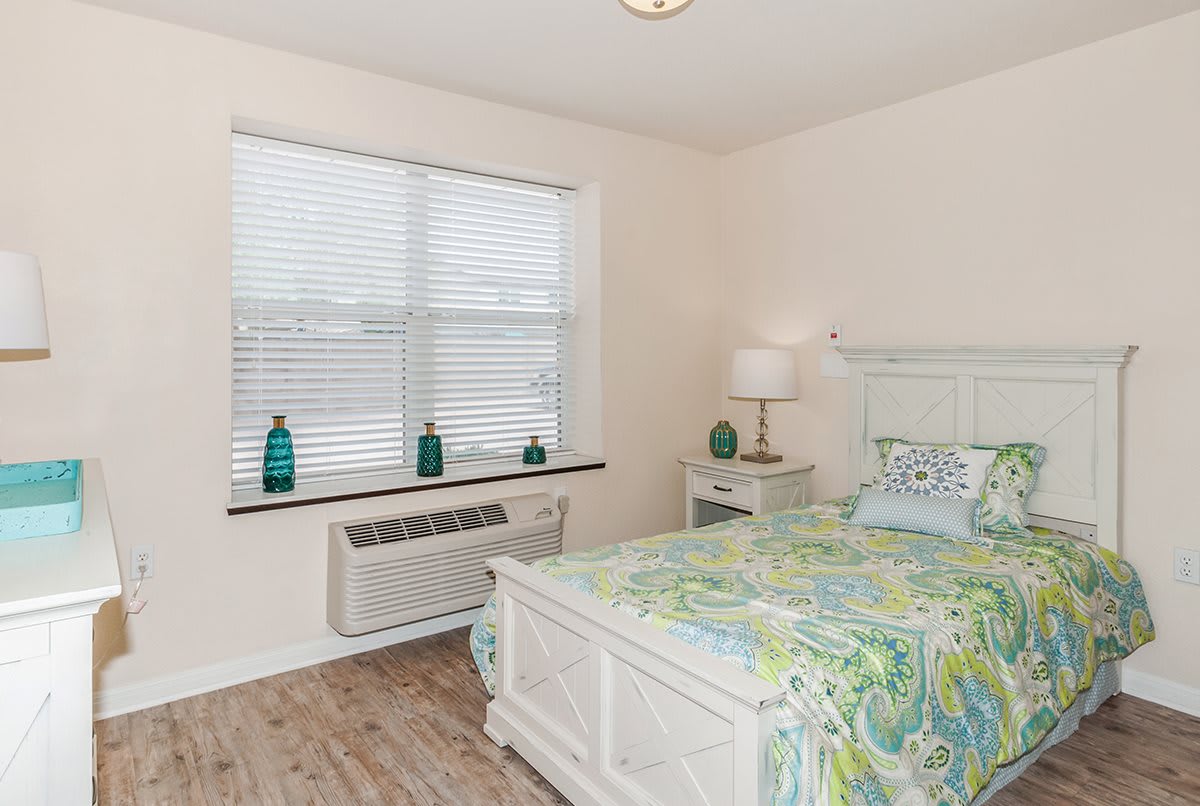 A cozy bedroom with a floral bedspread, white furniture, and decorative accents.