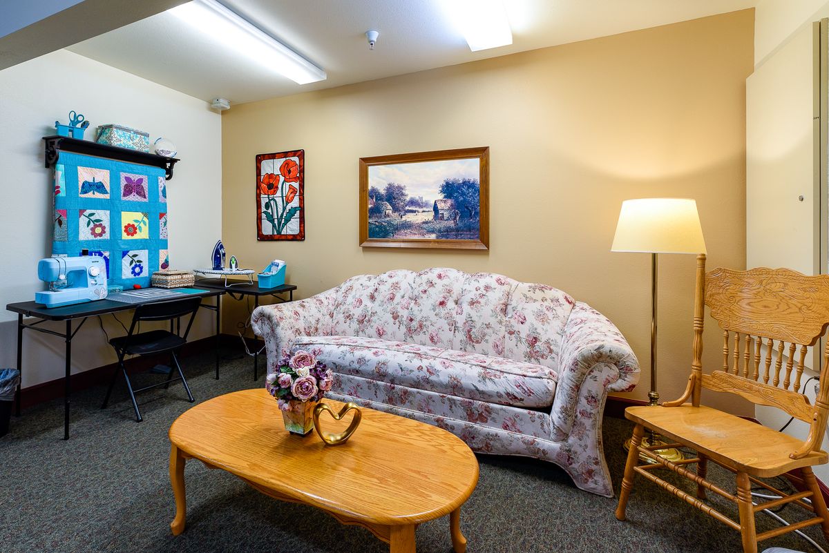 A cozy living room with a floral sofa, wooden coffee table, and artistic wall decorations.