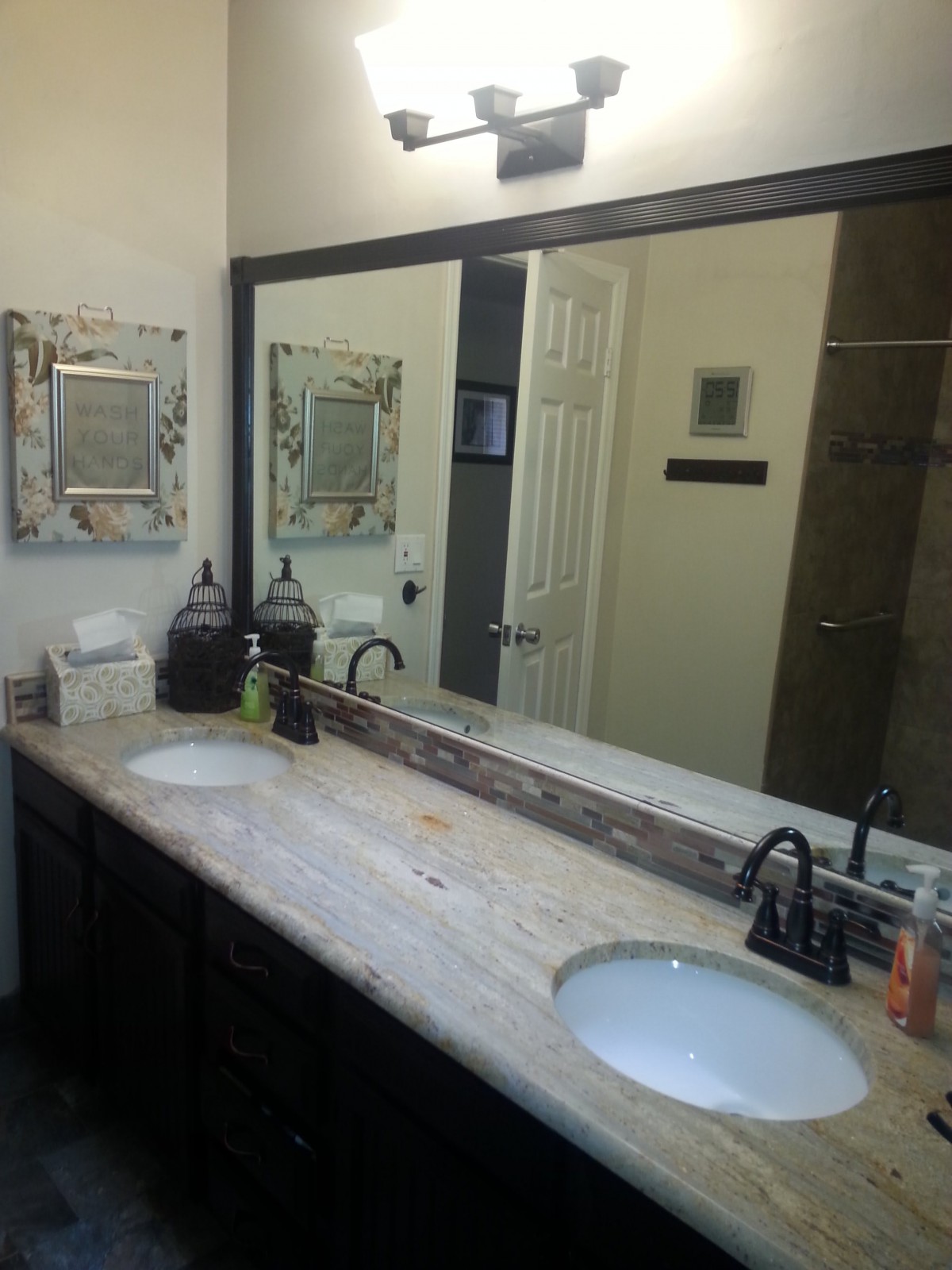 A modern bathroom with a large vanity mirror and double sinks.