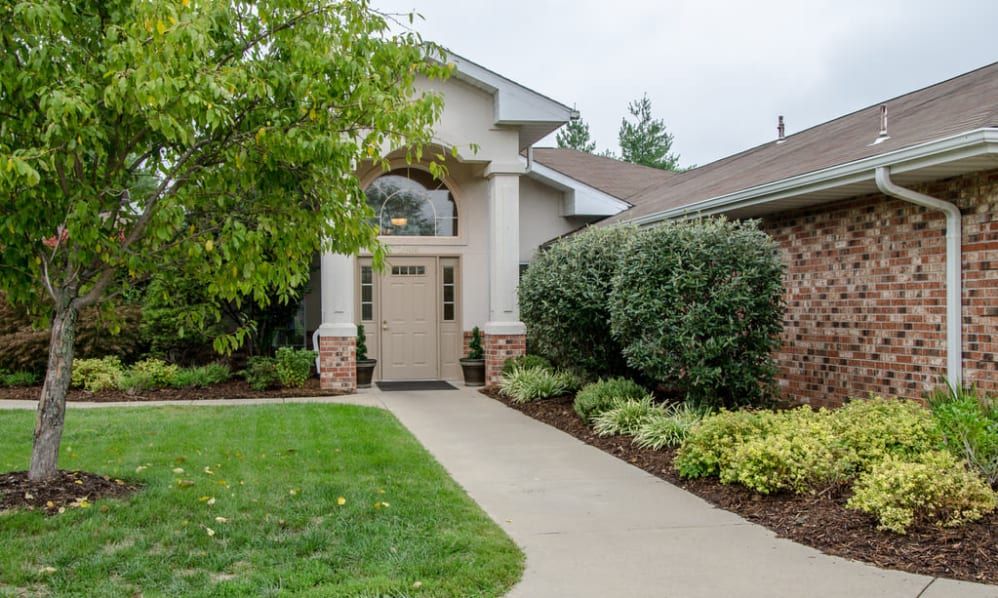 A welcoming house entrance with well-maintained landscaping and a paved pathway.