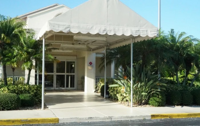 Entrance to a building with an awning and surrounding greenery.