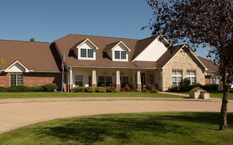 A large suburban house with a well-maintained lawn and clear blue sky.