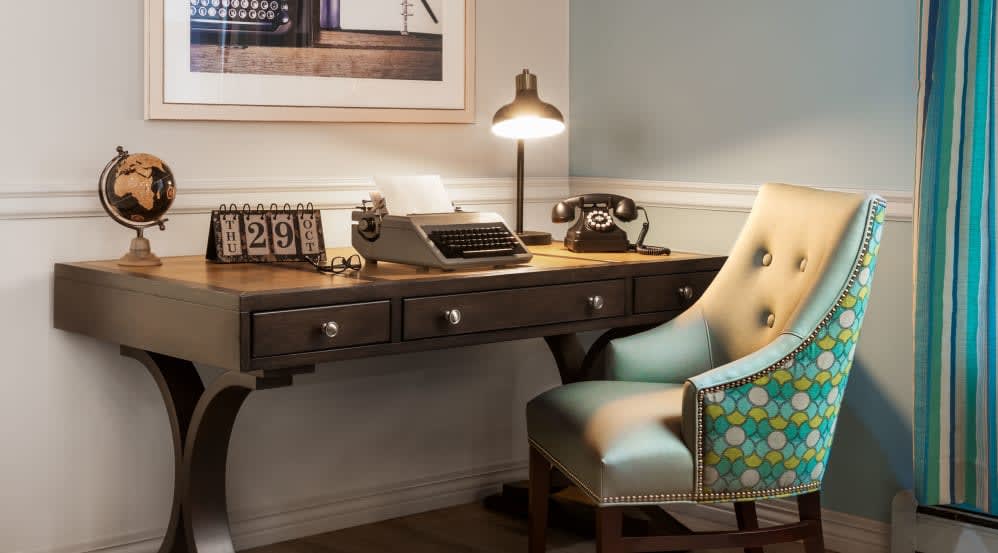 A cozy vintage workspace featuring a typewriter and rotary telephone.