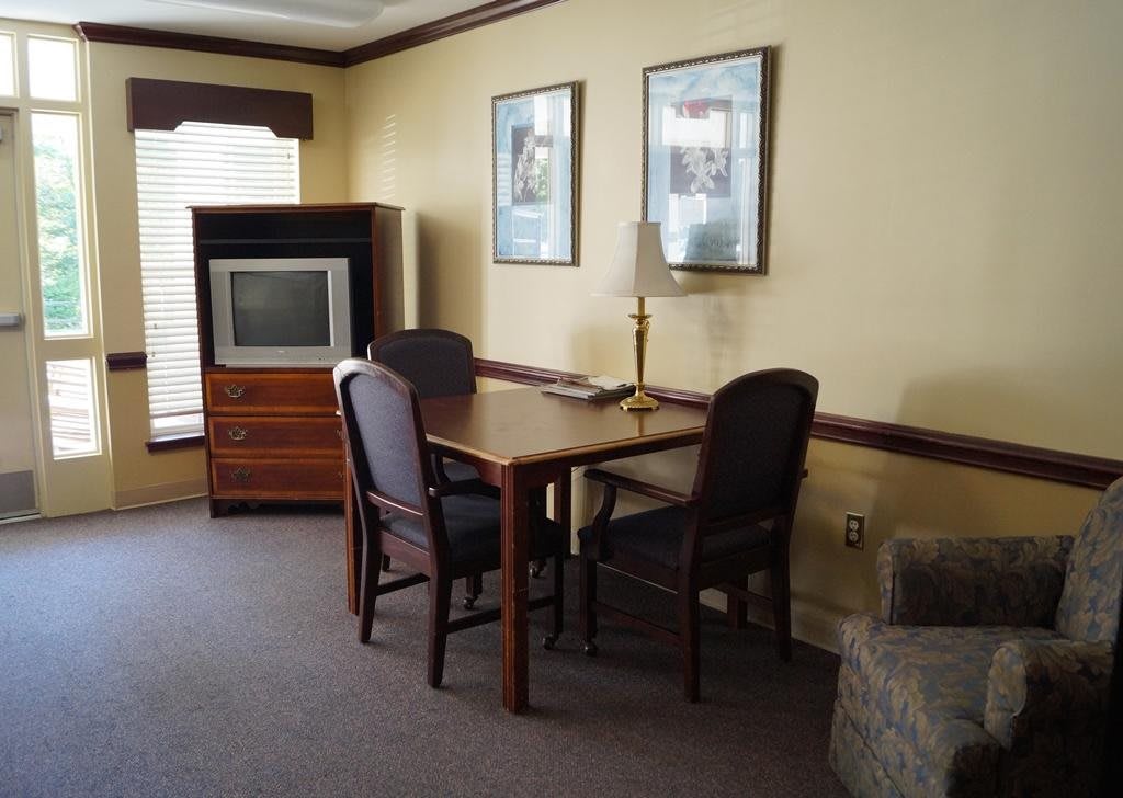 A cozy living room setup with a table, chairs, and an old-style TV.
