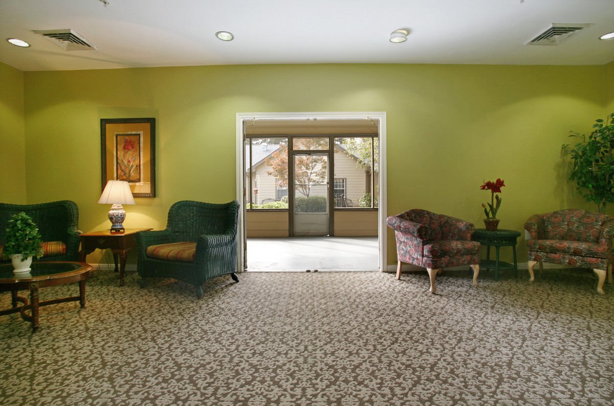 A cozy living room with armchairs and a patterned carpet, featuring a doorway leading to another room.