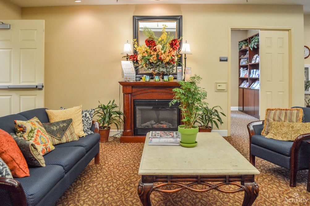 A cozy living room featuring a sofa, coffee table, fireplace, and decorative plants.