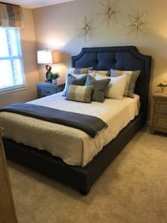 A cozy bedroom with a neatly made bed, decorative pillows, and soft lighting.