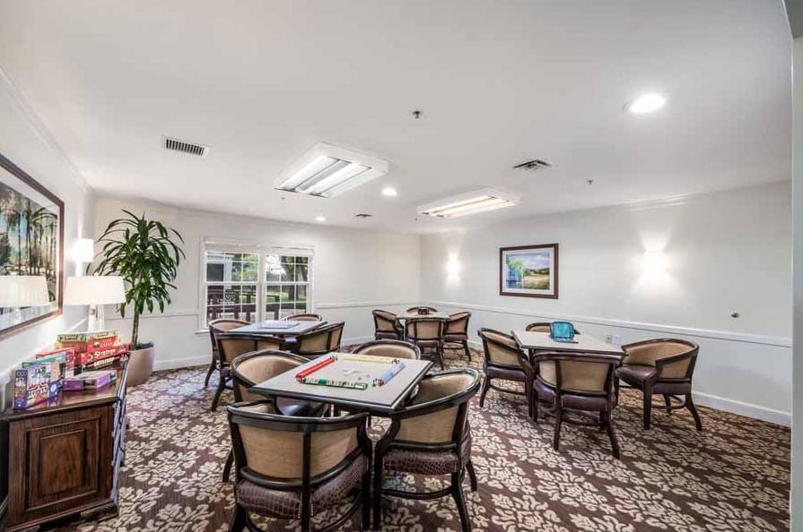 A well-lit meeting room with tables and chairs, featuring a carpeted floor and decorative elements.