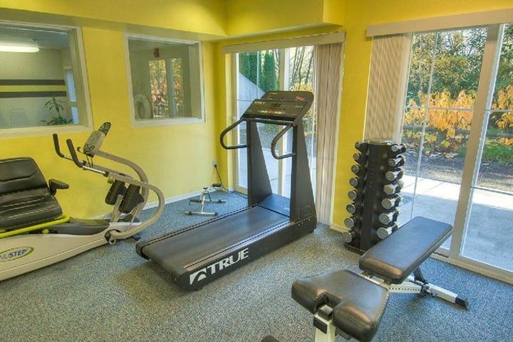 A small indoor gym with a treadmill, weights, and other exercise equipment.