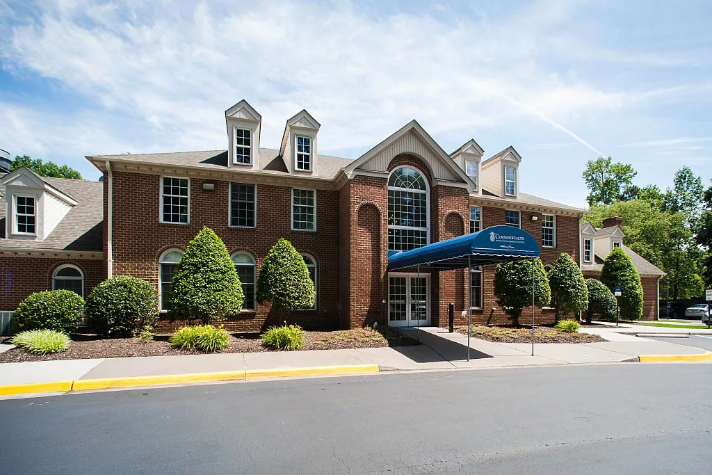A brick hotel with a blue awning over the entrance, surrounded by well-maintained landscaping.