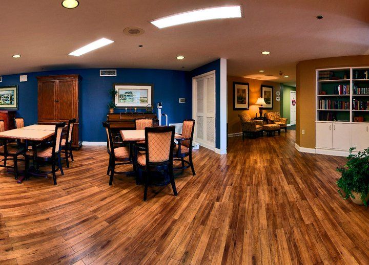 A spacious interior with a dining area featuring wood flooring, tables and chairs, complemented by wall art and soft lighting.