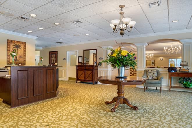 A cozy and elegant lobby featuring a reception desk, floral arrangement on a central table, and classic lighting.