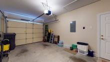 An empty garage interior with tools and a ladder against the wall.