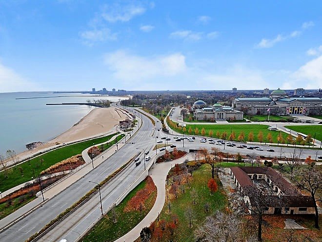 Aerial view of a waterfront cityscape with roads and a beach.