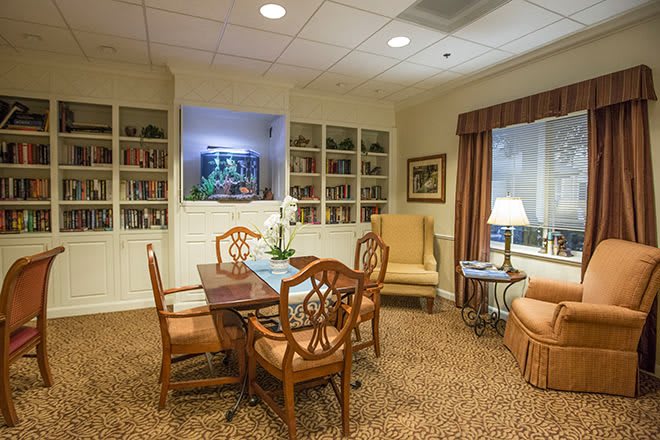 A cozy living room with a table and chairs, surrounded by bookshelves and comfortable seating.