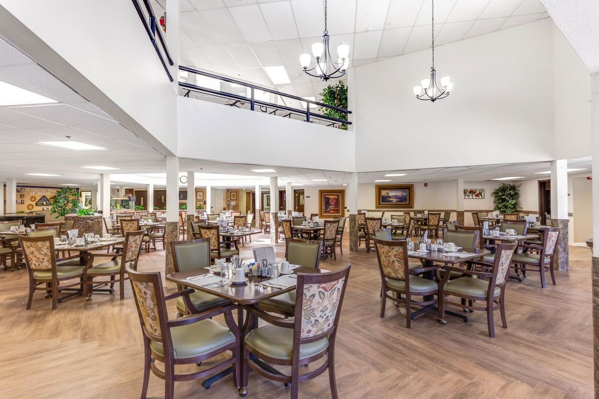 A spacious dining area with neatly arranged tables and chairs under elegant chandeliers.