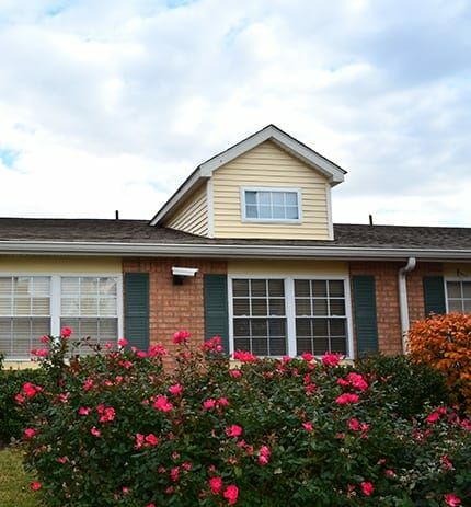 A charming house with a brick facade and a front garden filled with blooming flowers.