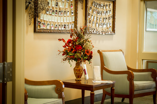 A cozy waiting area featuring elegant chairs, a decorative flower arrangement, and framed photographs on the wall.