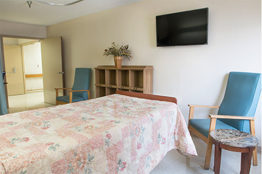 A well-furnished hospital room featuring a bed, a television, and comfortable seating.