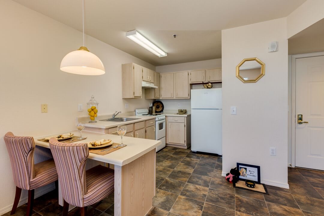 A cozy apartment kitchen with a small dining area, featuring modern appliances and a tiled floor.