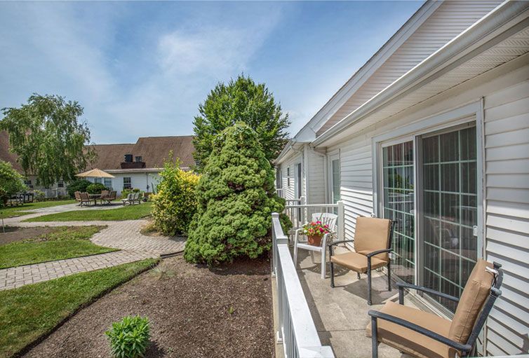 A cozy outdoor patio area with chairs overlooks a well-maintained garden and pathway.