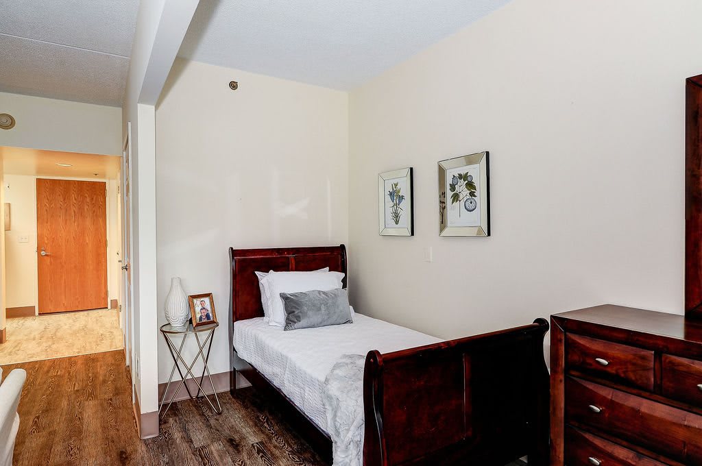 A cozy bedroom with a single bed, white linens, and framed wall art.