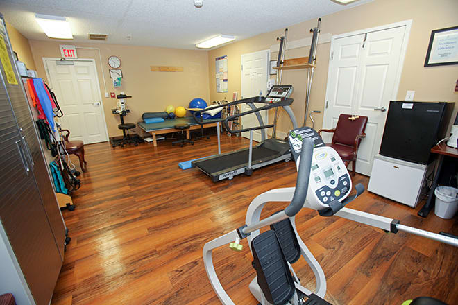 A well-equipped fitness room featuring a treadmill and various exercise machines on a wooden floor.
