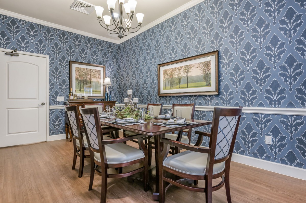 A beautifully decorated dining room with elegant wallpaper and a classic chandelier.