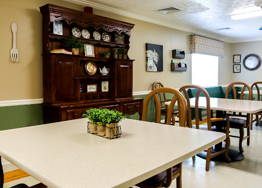 A cozy dining area featuring a wooden cabinet, a simple table, and comfortable chairs, accented with decorative plants.