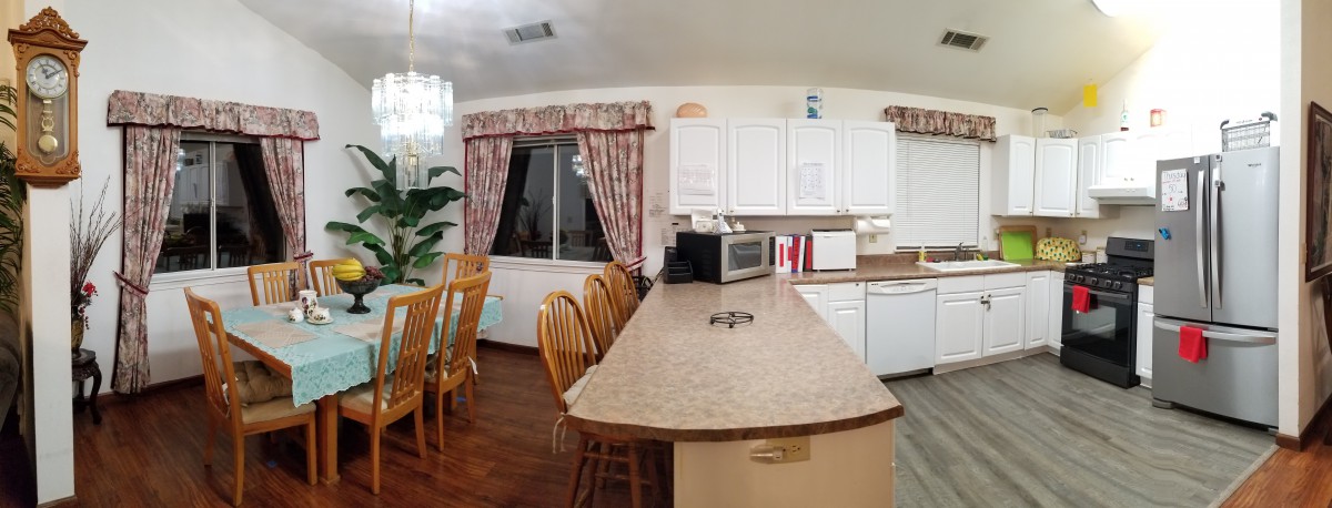 A cozy kitchen and dining area with a countertop, wooden chairs, and decorative curtains.