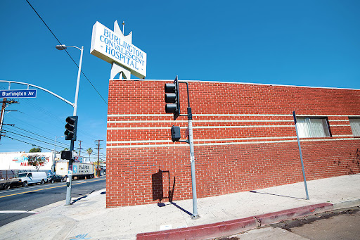 A sunlit view of a brick building with a prominent sign and traffic light against a clear blue sky.