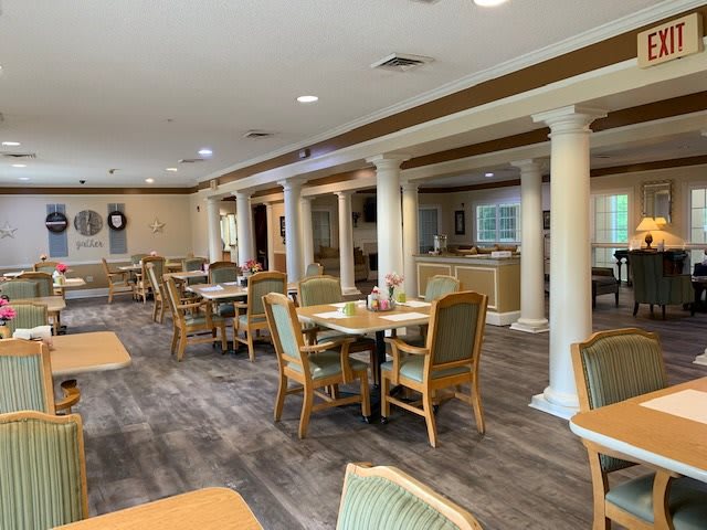 An elegantly designed dining area with wooden tables and cushioned chairs, featuring decorative pillars and a cozy ambiance.