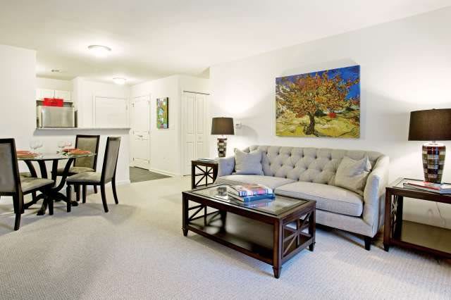 A modern living room featuring a stylish sofa and coffee table, complemented by wall art and ambient lighting.