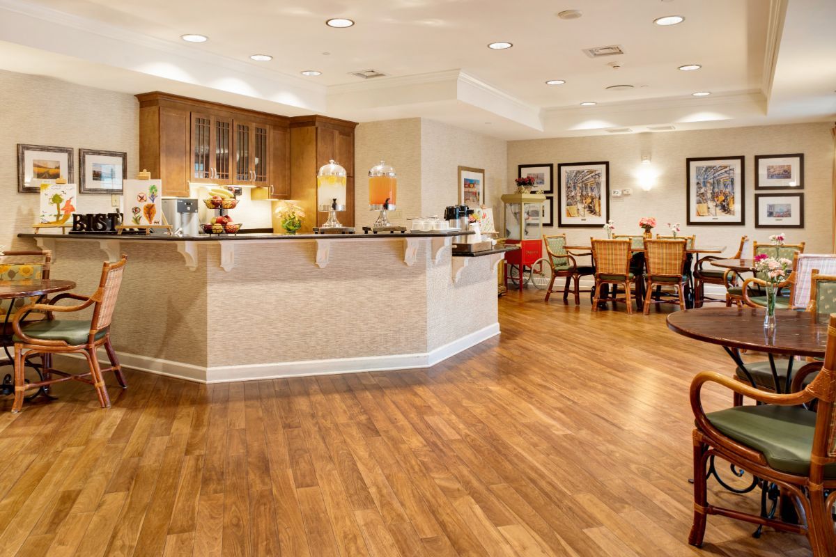 A spacious and elegantly designed interior with a wooden floor, featuring a kitchen counter and a dining area.