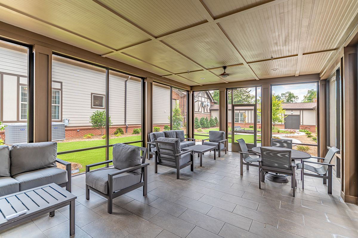 A modern screened porch with comfortable outdoor seating overlooking a garden.