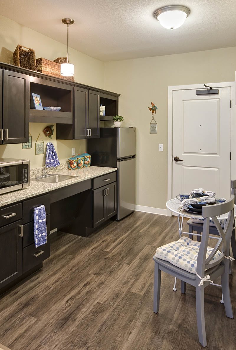A modern kitchen with dark cabinets, stainless steel appliances, and a small dining area.
