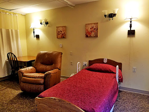 A cozy room featuring a single bed, a comfortable armchair, and decorative wall art.