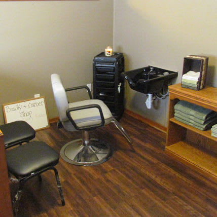 A small salon setup with a styling chair, sink, and shelving.
