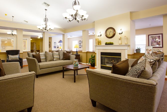 A cozy living room featuring comfortable sofas arranged around a fireplace, with elegant chandeliers illuminating the space.