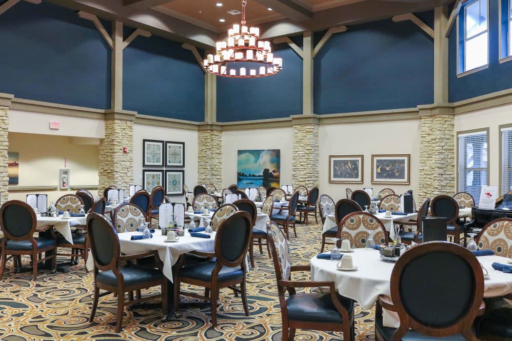 Elegant dining room with beautifully set tables and a large chandelier.