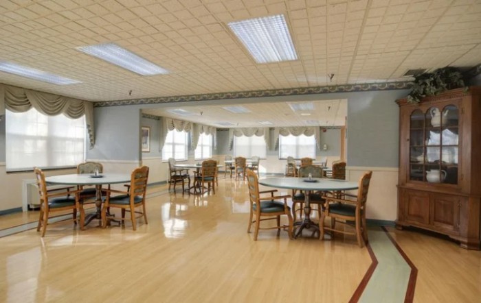 An empty dining area with several tables and chairs, well-lit with ceiling lights.