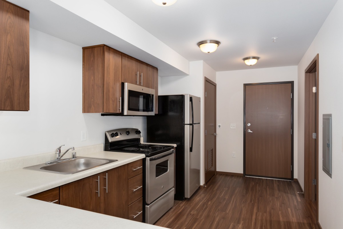 A modern kitchen featuring wooden cabinets and stainless steel appliances, including a microwave, oven, and refrigerator.